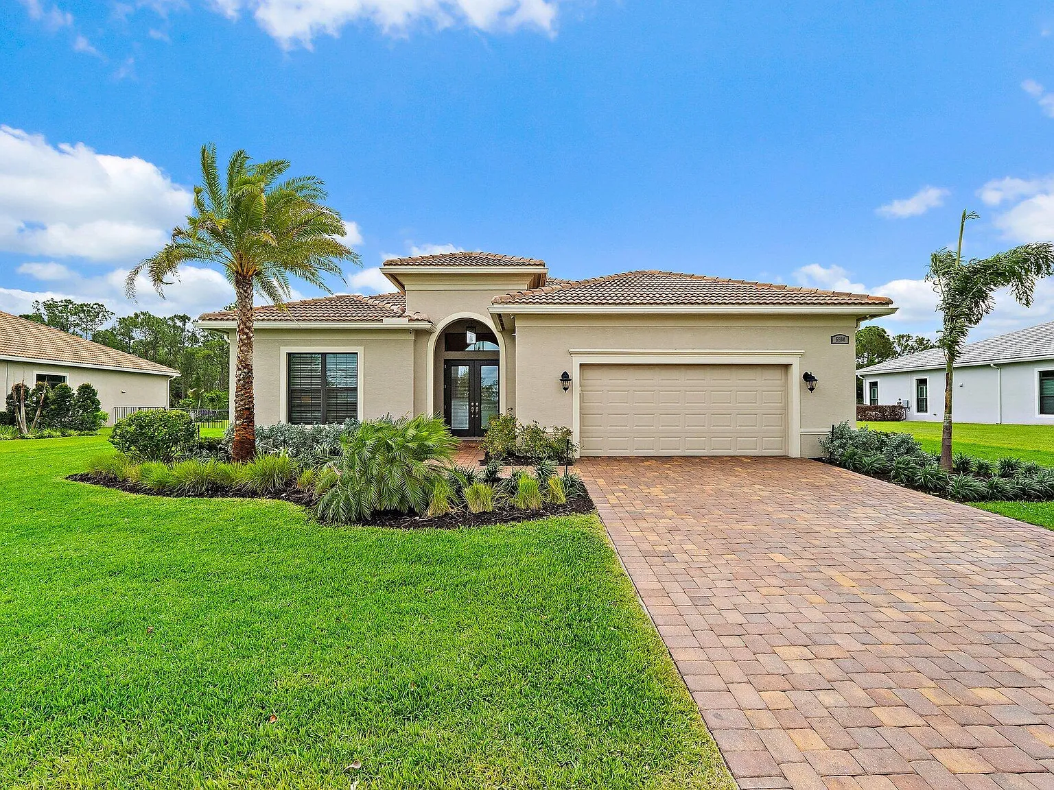 A Camiso Holdings managed home — single-story Florida property with tile roof, paver driveway, and mature palms