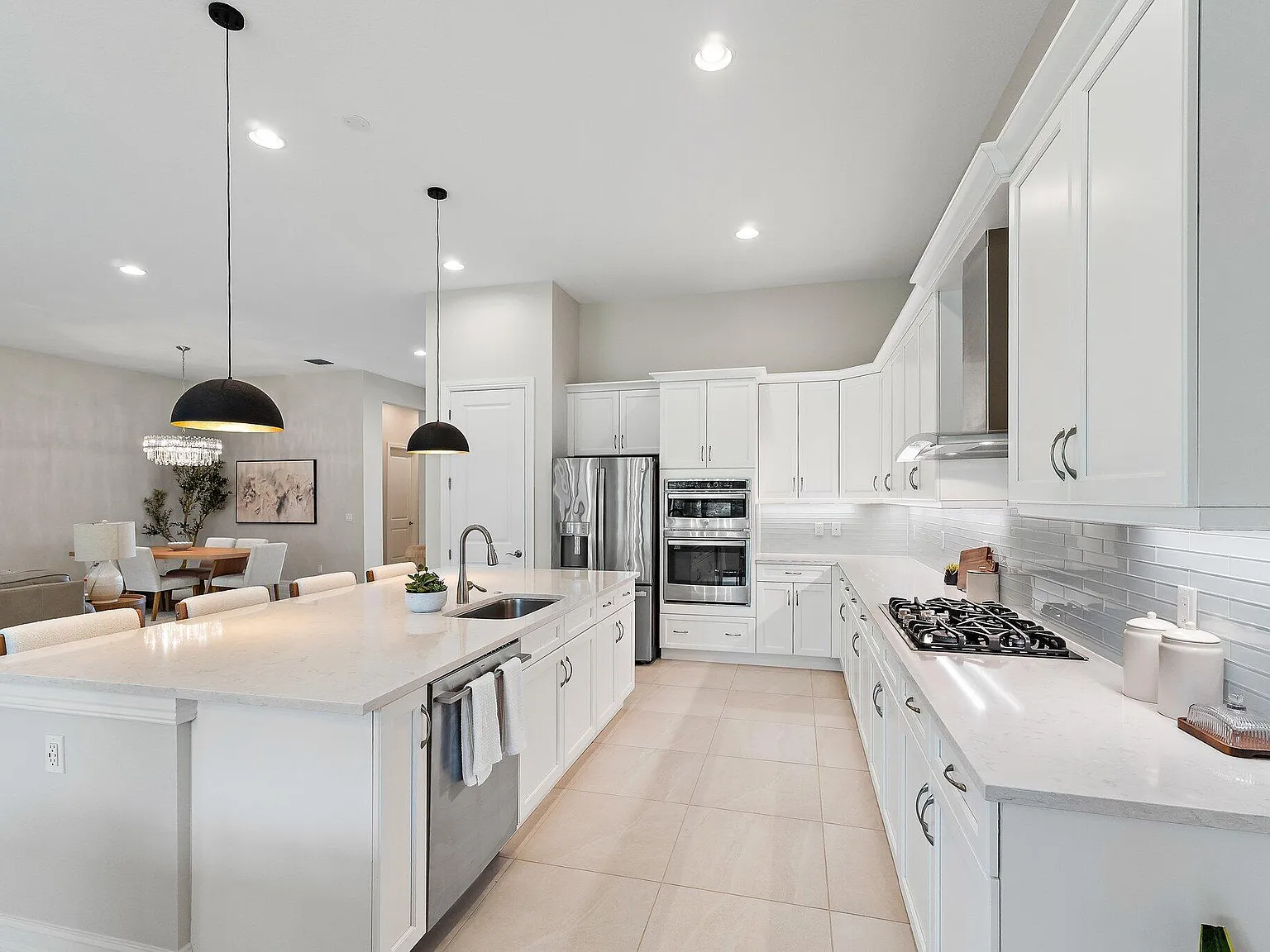 Kitchen with white cabinets, quartz island, gas cooktop, and stainless appliances