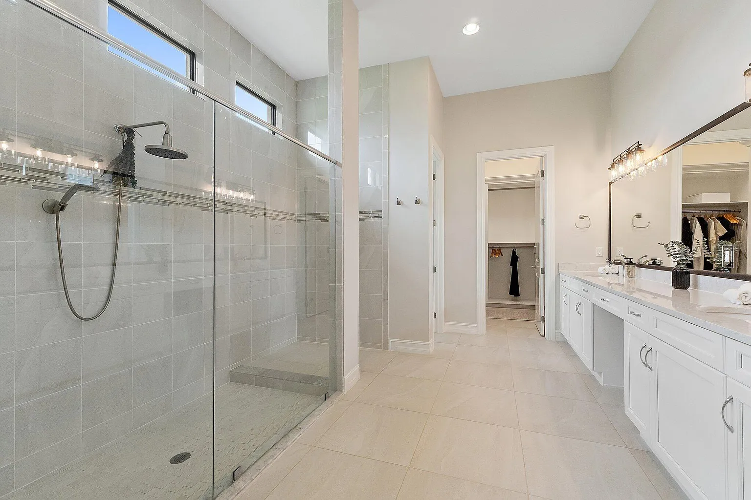 Primary bathroom with walk-in glass shower, double vanity, and walk-in closet